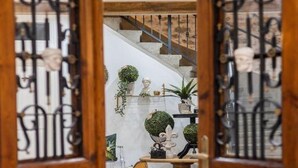 A wooden door with intricate metalwork, leading to a staircase with a white wall and decorative plants. - History House Moja Ti 1830 - Deluxe Apartment (Senj)