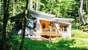 Eine Holzhütte mit einer Veranda, umgeben von Bäumen.