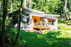 Eine Holzhütte mit einer Veranda, umgeben von Bäumen.