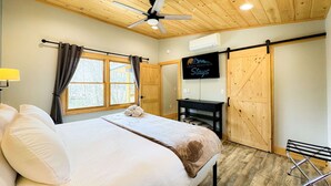 Ein Schlafzimmer mit einem Bett, einem Deckenventilator, einem Fernseher und einer Schiebetür.