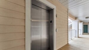 Un ascenseur moderne avec une finition métallique, un mur en bois et un plancher en bois.