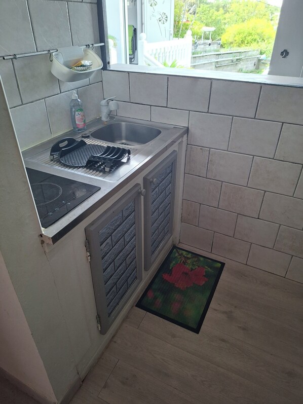 A compact kitchen with a sink, stove, and a small window overlooking a garden.