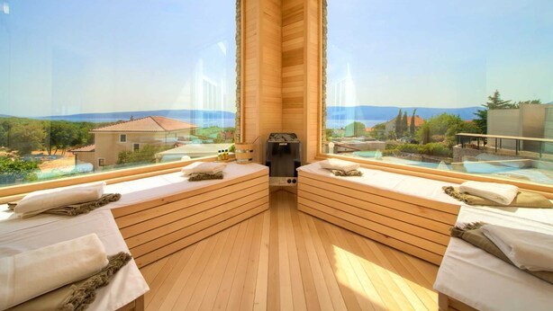 Una sauna in legno con panche e un apparecchio per sauna, con vista su una piscina e un paesaggio suggestivo.