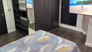 A bedroom with a bed, a wardrobe, a television, and a door with a beach scene.