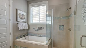 Een moderne badkamer met een glazen douchecabine, een vrijstaand bad en een decoratief muurschildering van een zeemeermin.