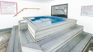 A hot tub with steps leading up to it, surrounded by white walls. There are signs with rules for using the hot tub and spa area. - 3 Min to Strip! Large Condo, Arcade Game, Pools, Hot tub, Sauna, Golf & Shows! (Branson)