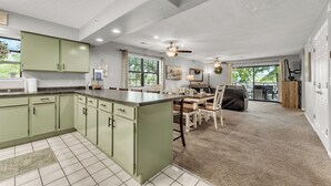 A spacious kitchen with green cabinets, a large island, and a dining area with wooden chairs and a table. - 3 Min to Strip! Large Condo, Arcade Game, Pools, Hot tub, Sauna, Golf & Shows! (Branson)