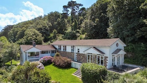 A two-story house with a garden, a conservatory, and a stone wall. - Beach Haven (Wadebridge)