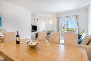 Un salon moderne comprenant une table à manger, des chaises, un téléviseur et un canapé.