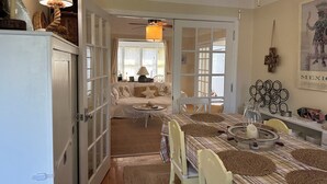 Un comedor con una mesa preparada para dos personas, una araña y un cuadro en la pared.