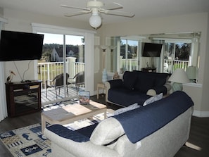 Relax in this stylish living room with a large flat-screen TV, comfortable seating area, and a beautiful view of the outdoors.