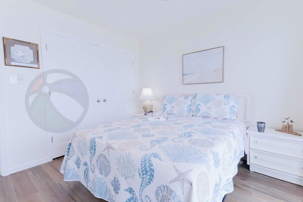 A bedroom with a bed, a nightstand, a lamp, and a framed picture on the wall.