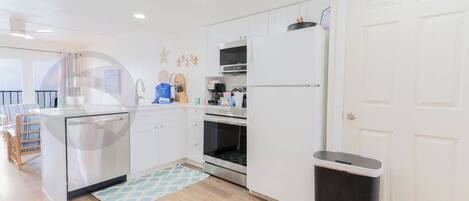 Una cocina moderna con armarios blancos, lavavajillas, refrigerador y horno.
