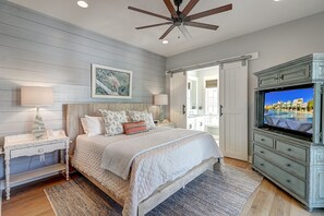 A bedroom with a bed, nightstands, a television, and a ceiling fan. - The Reel Deal 222 GR (Port Aransas)