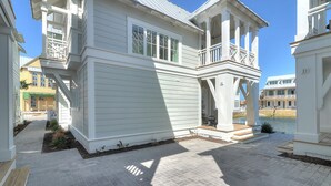 A two-story house with a covered patio and a view of a body of water. - Glass Half Full 205 Fiv-g (Port Aransas)