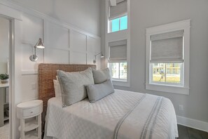 Une chambre à coucher avec un grand lit, une table de chevet, une lampe et une fenêtre donnant sur l’extérieur.
