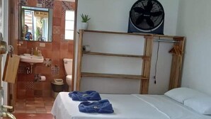 A bedroom with a bed, a fan, and a bathroom visible through an open door. - Hotel Pura Natura (Colorado)