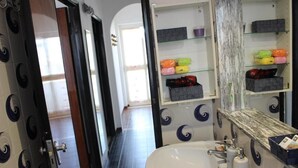 A bathroom with a white sink, a mirror, and shelves with toiletries. - Appartamento a 100 Metri dal Mare - Tutti i Comfort- Free Wi-fi (Ostuni)