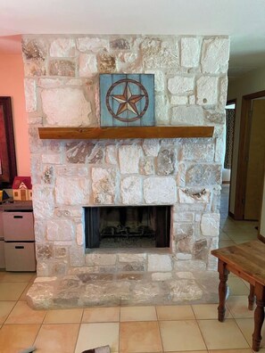 A stone fireplace with a star compass decoration above it. - Ranchito | Hilltop Cabin w/ Hot Tub & Scenic Views (Hondo)
