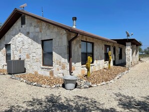 A stone building with a sloped roof, a satellite dish, and a cactus in the foreground.