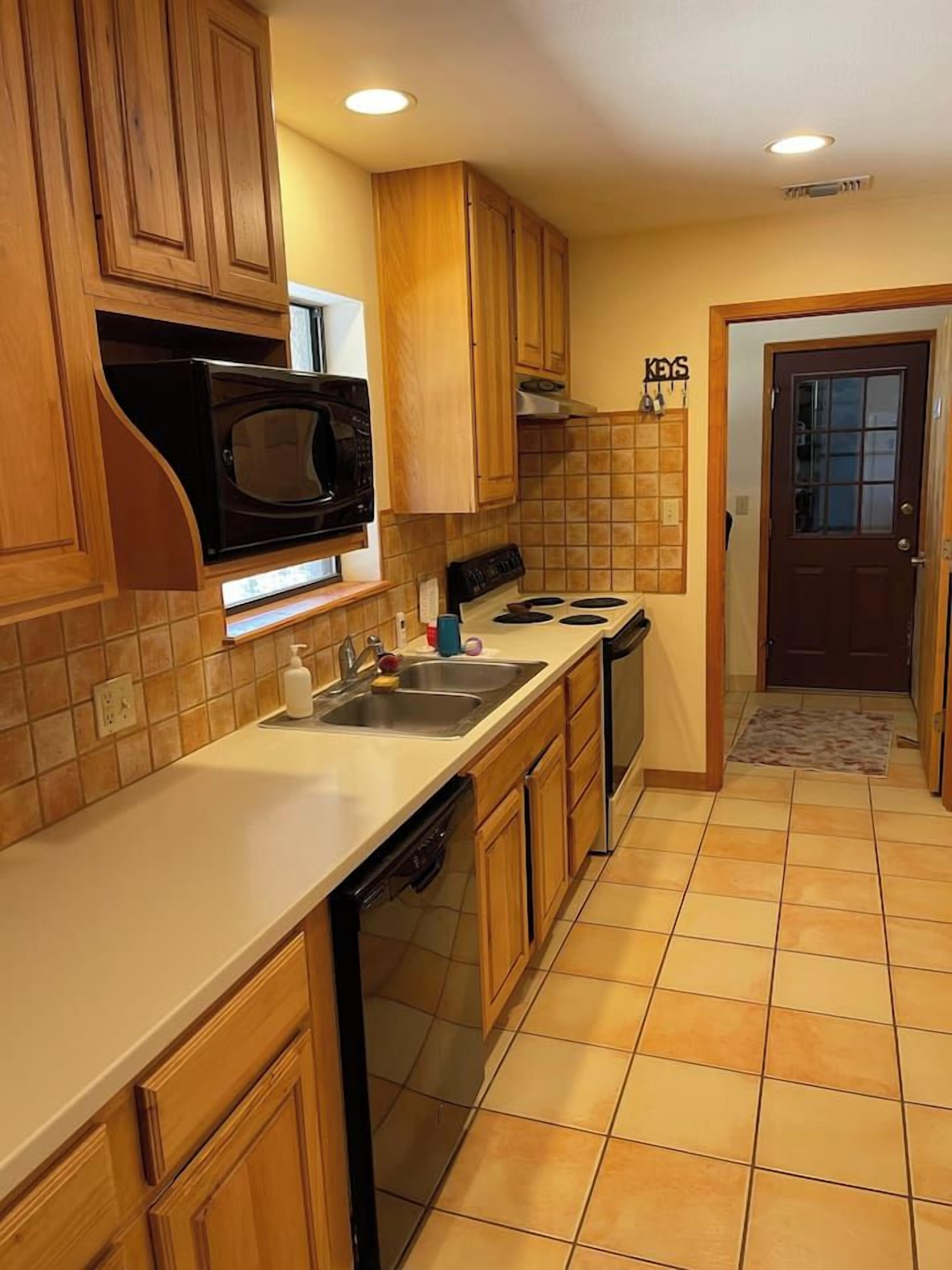A kitchen with wooden cabinets, a microwave, a stove, and a sink.