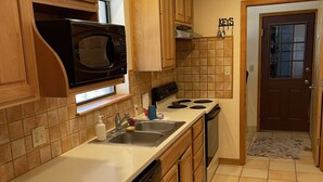 A kitchen with wooden cabinets, a microwave, a stove, and a sink. - Ranchito in Hondo Texas (Hondo)