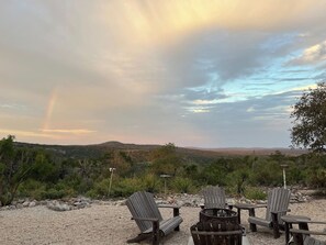 A desert landscape with a fire pit and Adirondack chairs. - Ranchito | Hilltop Cabin w/ Hot Tub & Scenic Views (Hondo)
