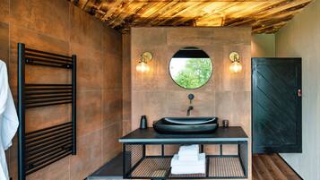A modern bathroom with a black sink, a towel rack, and a wooden ceiling.