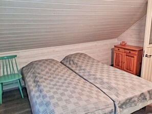 Quarto com beliche, um pequeno armário de madeira e uma cadeira verde.