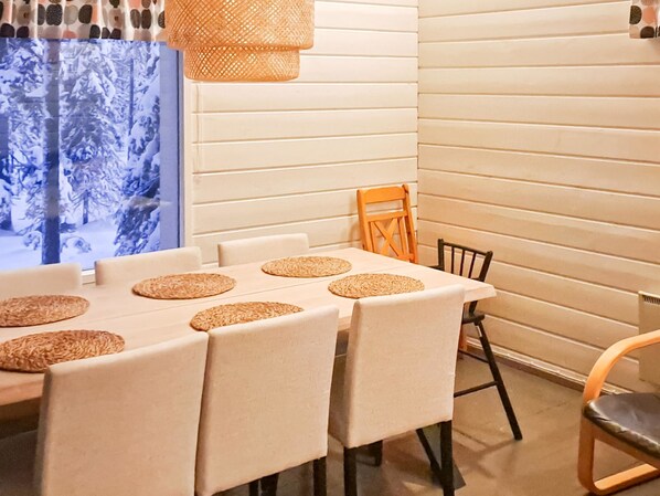 A dining area with a table set for four, featuring woven placemats and chairs with a light fabric upholstery.