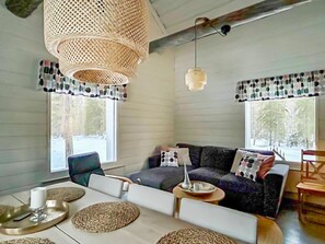 A cozy living room with a sofa, chairs, a coffee table, and a hanging light fixture.
