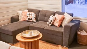 A modern living room with a grey sectional sofa, patterned cushions, and a woven coffee table. - Pajalan piilopirtti by Interhome (Kuusamo)