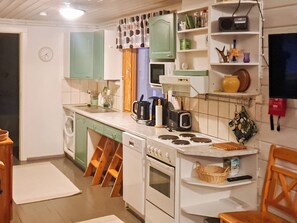 A kitchen with a stove, sink, and various appliances. There is a microwave, a kettle, and a toaster on the counter. - Pajalan piilopirtti by Interhome (Kuusamo)