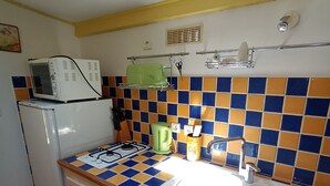A kitchen with a tiled backsplash, a sink, a stove, and a microwave. - La Chenaie (Mazan)