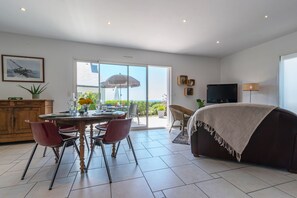 Ein geräumiger Wohnbereich mit Esstisch, Stühlen, einer Couch und einem Fernseher.