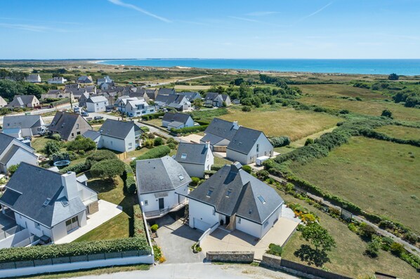 A residential area with houses, a clear sky, and a coastline in the background.