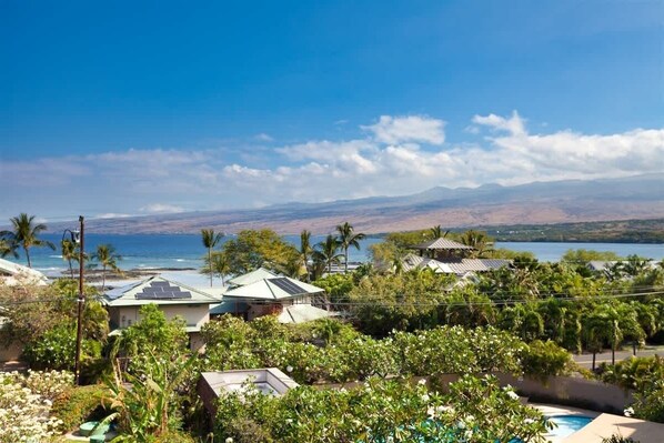 A coastal property with multiple houses, a swimming pool, and a view of the ocean and mountains.