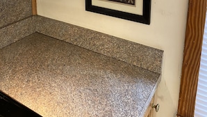 A framed picture on a wall with a countertop below.