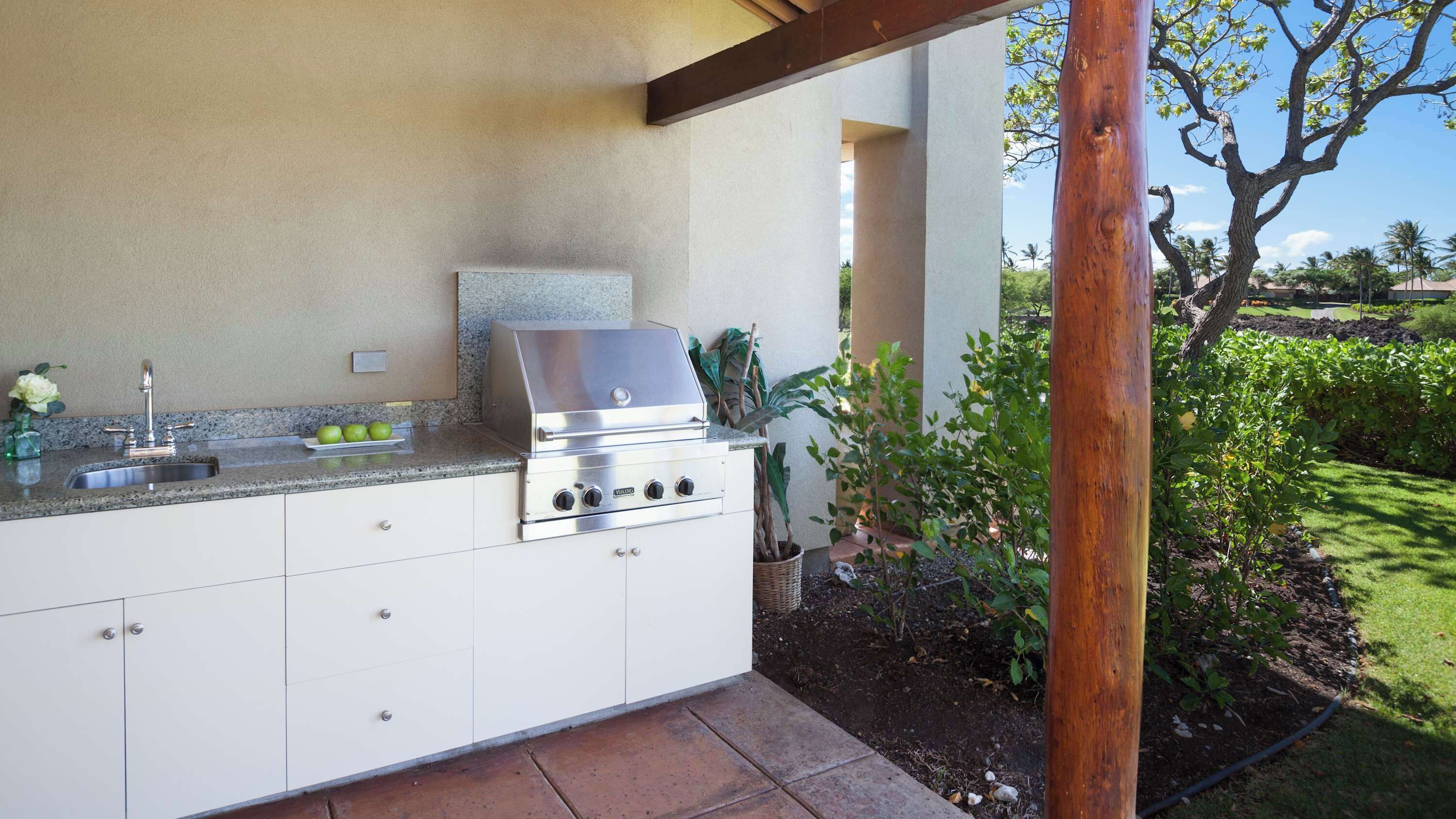 Cocina exterior con una parrilla de acero inoxidable, un lavamanos y una encimera.