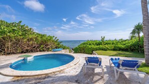 A pool with lounge chairs, a view of the ocean, and lush greenery. - Stunning 5BR Balam Ek Villa – Oceanfront, Pool & Exceptional Views (Akumal)