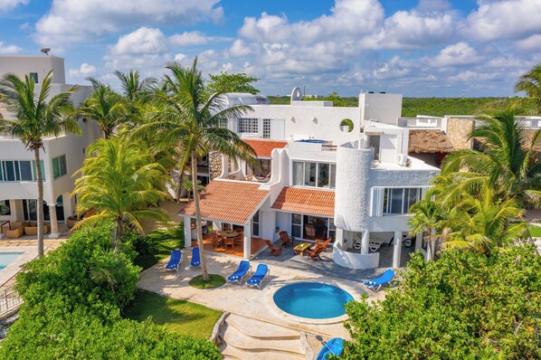 A modern villa with a swimming pool, palm trees, and a clear view of the surrounding landscape.