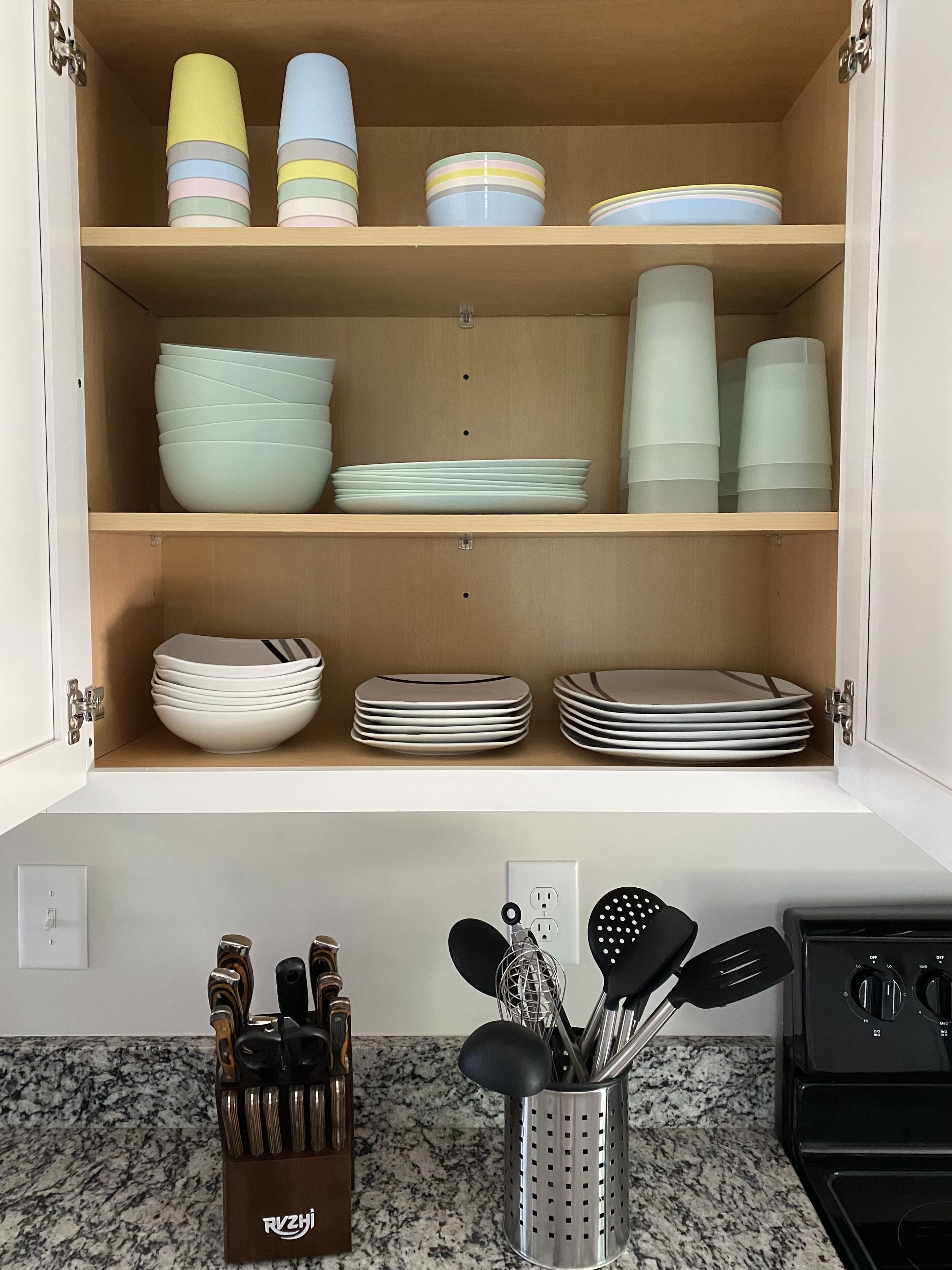 Un armario de cocina con repisas que contienen diferentes platos y utensilios.