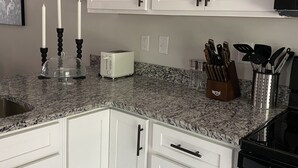 A kitchen with white cabinets, a granite countertop, a toaster, and a knife block.