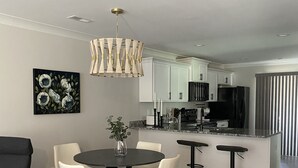A modern kitchen with white cabinets, a black refrigerator, and a built-in island with bar stools.