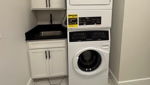 A laundry room with a stacked washer and dryer, a sink, and cabinets.