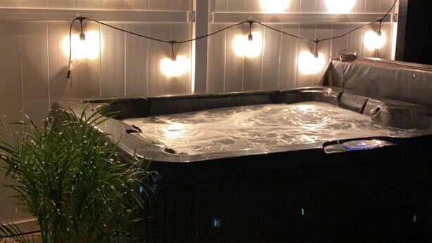 A hot tub with string lights in the background.