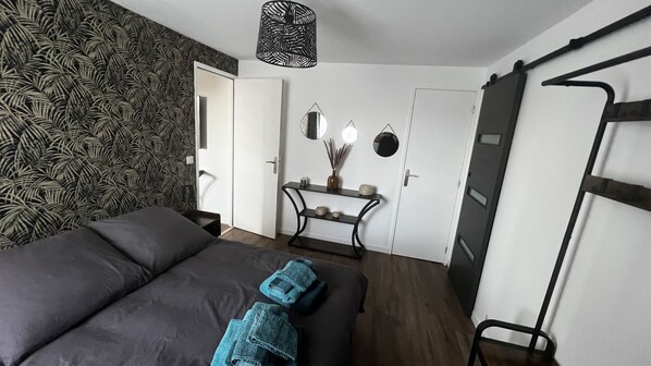 Une chambre à coucher comprenant un lit, une console ornée d’objets décoratifs, un miroir et une armoire.