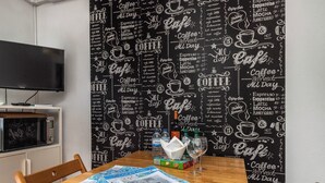 Ein Essbereich mit einer Tafelwand, die Zeichnungen und Text zum Thema Kaffee zeigt, einem Holztisch mit Speisekarten und einer Mikrowelle auf einem Regal.