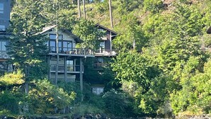 Un chalet au bord du lac, doté d’un quai, entouré d’une forêt dense et situé au pied d’une colline.