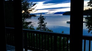Une terrasse en bois offrant une vue sur un lac et des montagnes lointaines.